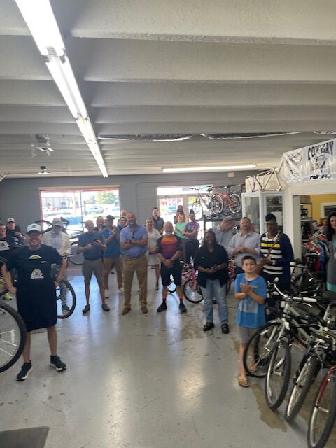 Attendees to the ribbon cutting ceremony look inside the shop and pose for a photo.